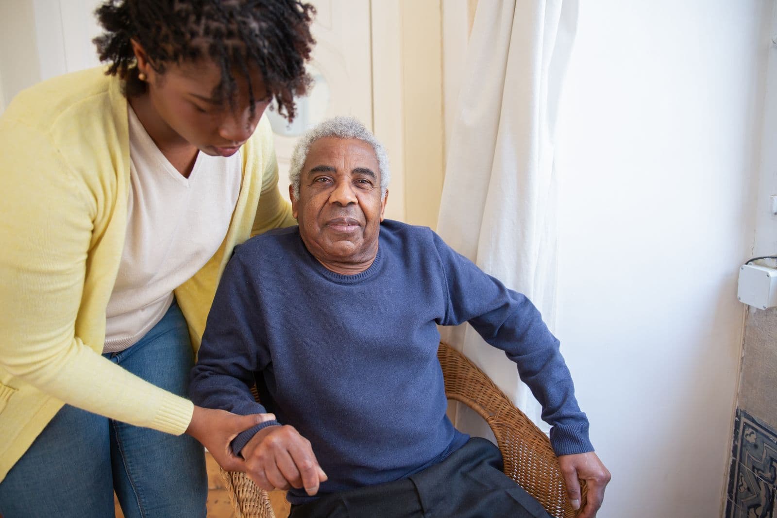 A woman offering an older man a helping hand at home